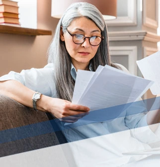 Woman looking over paperwork with laptop