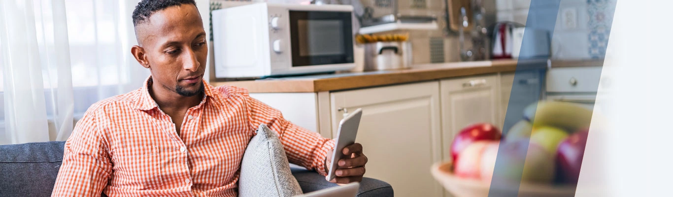 african american man couch laptop cell phone